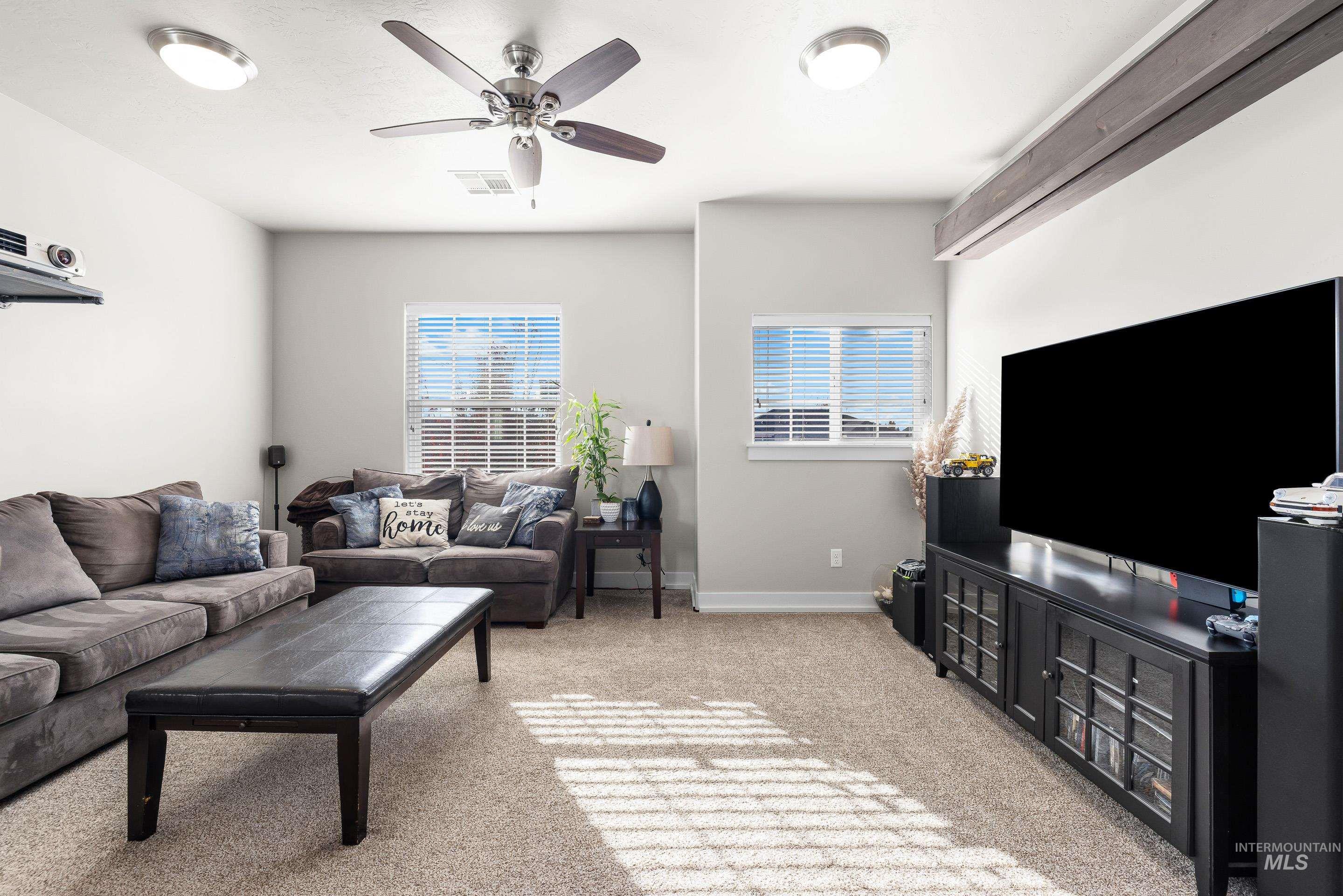 Living area with light colored carpet, healthy amount of natural light, and ceiling fan
