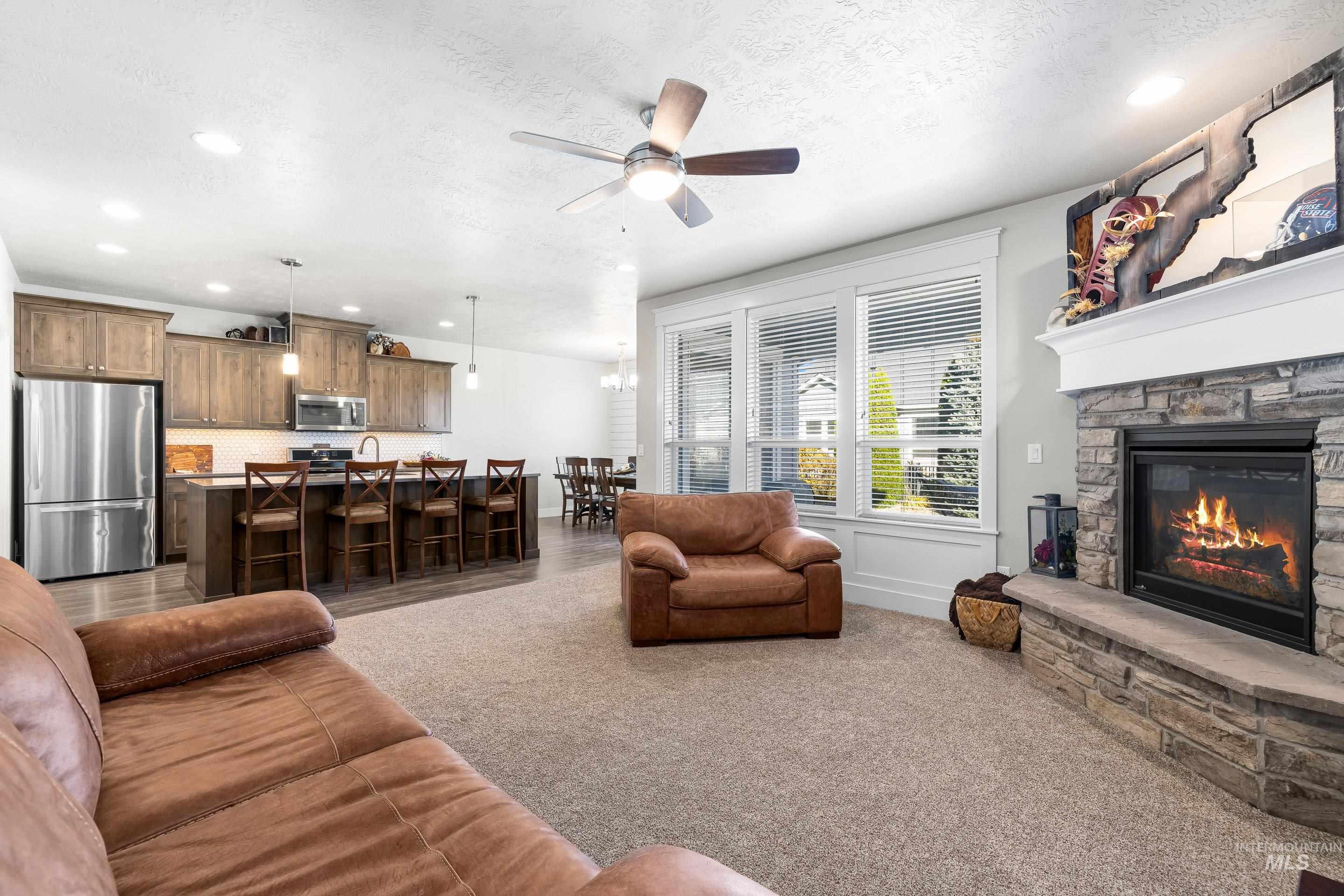 Living area with recessed lighting, ceiling fan, a textured ceiling, carpet, and a fireplace