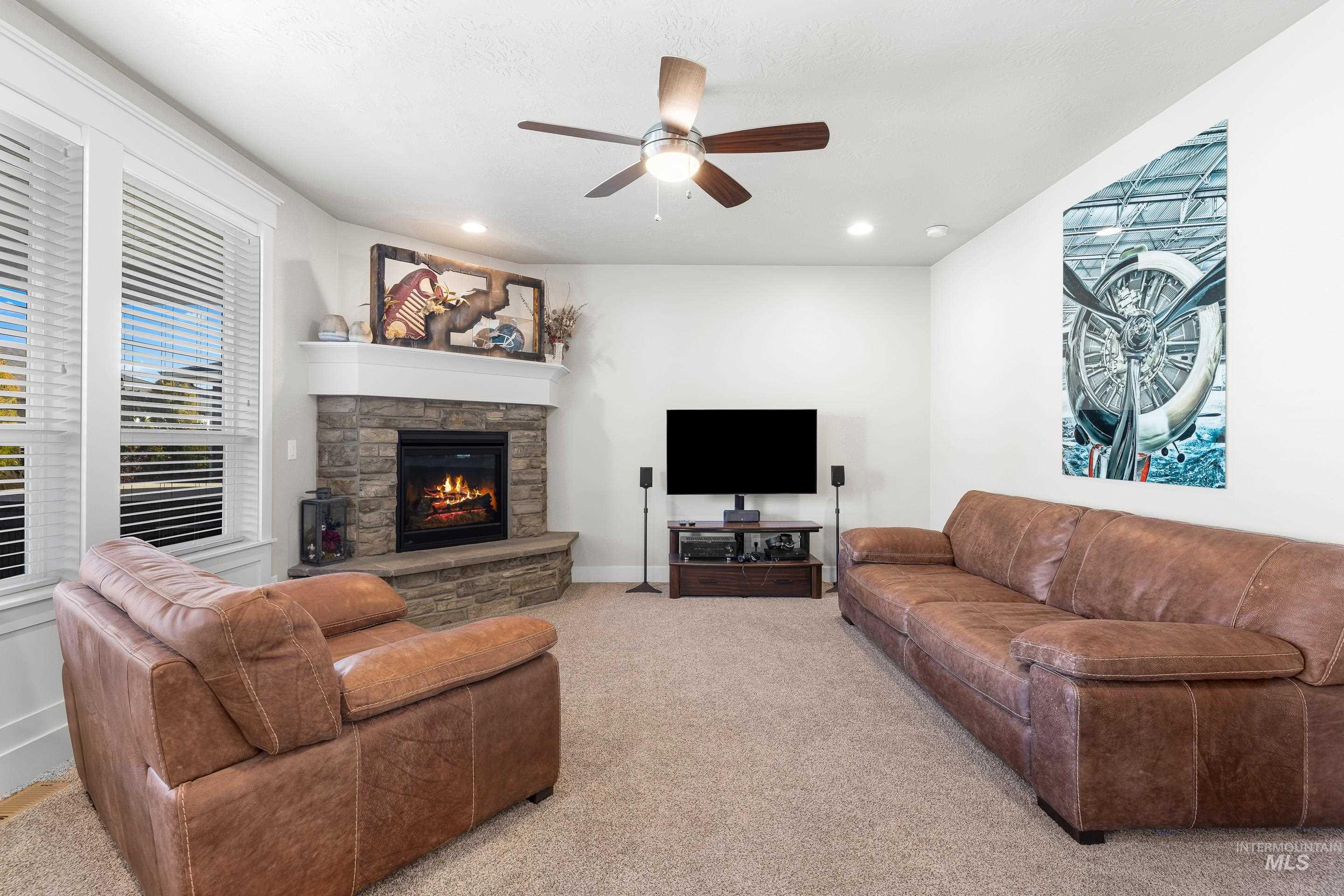 Carpeted living room with a fireplace, a ceiling fan, and recessed lighting