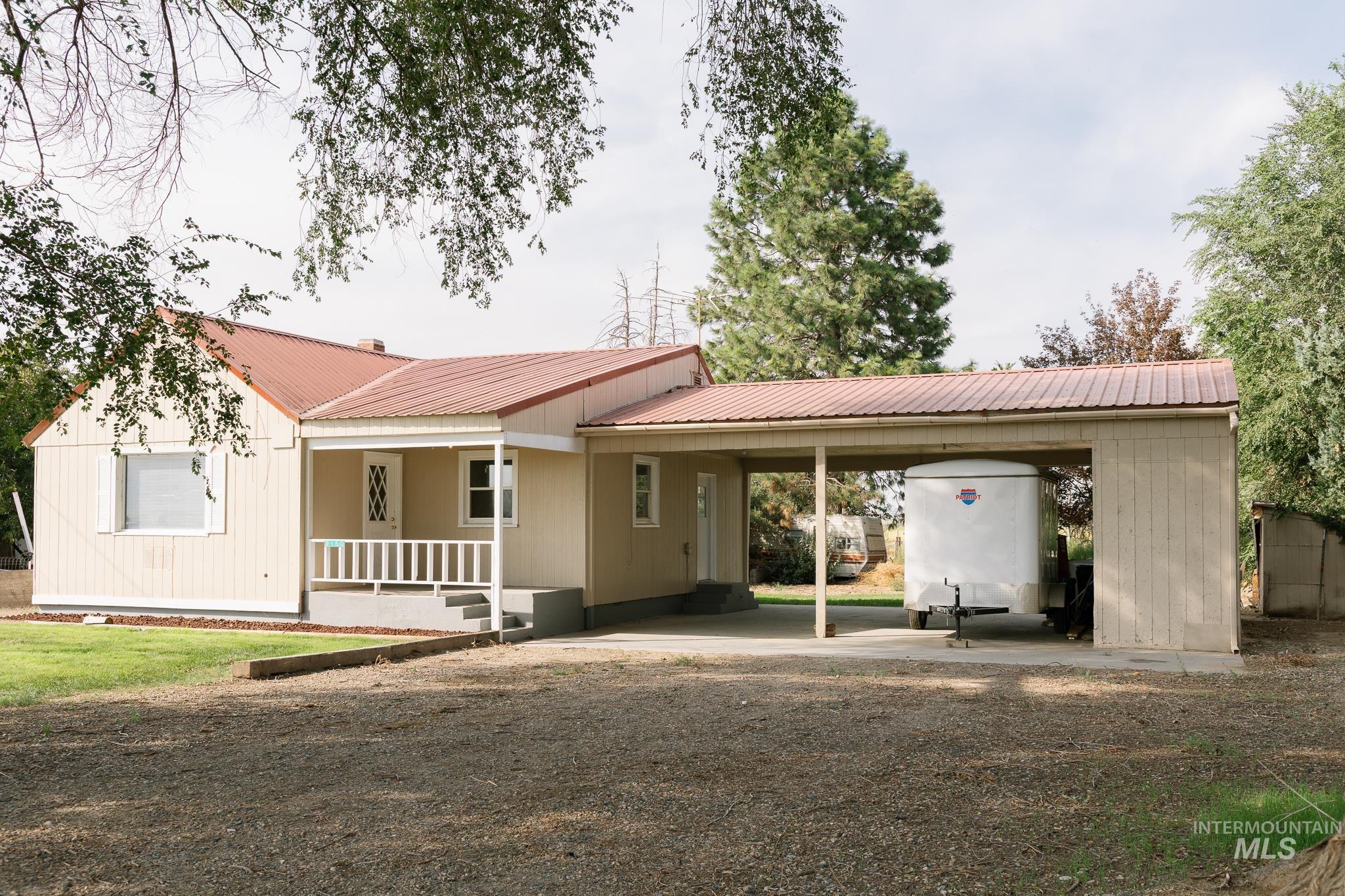 View of front of property with a carport, a metal roof, a porch, and a front yard