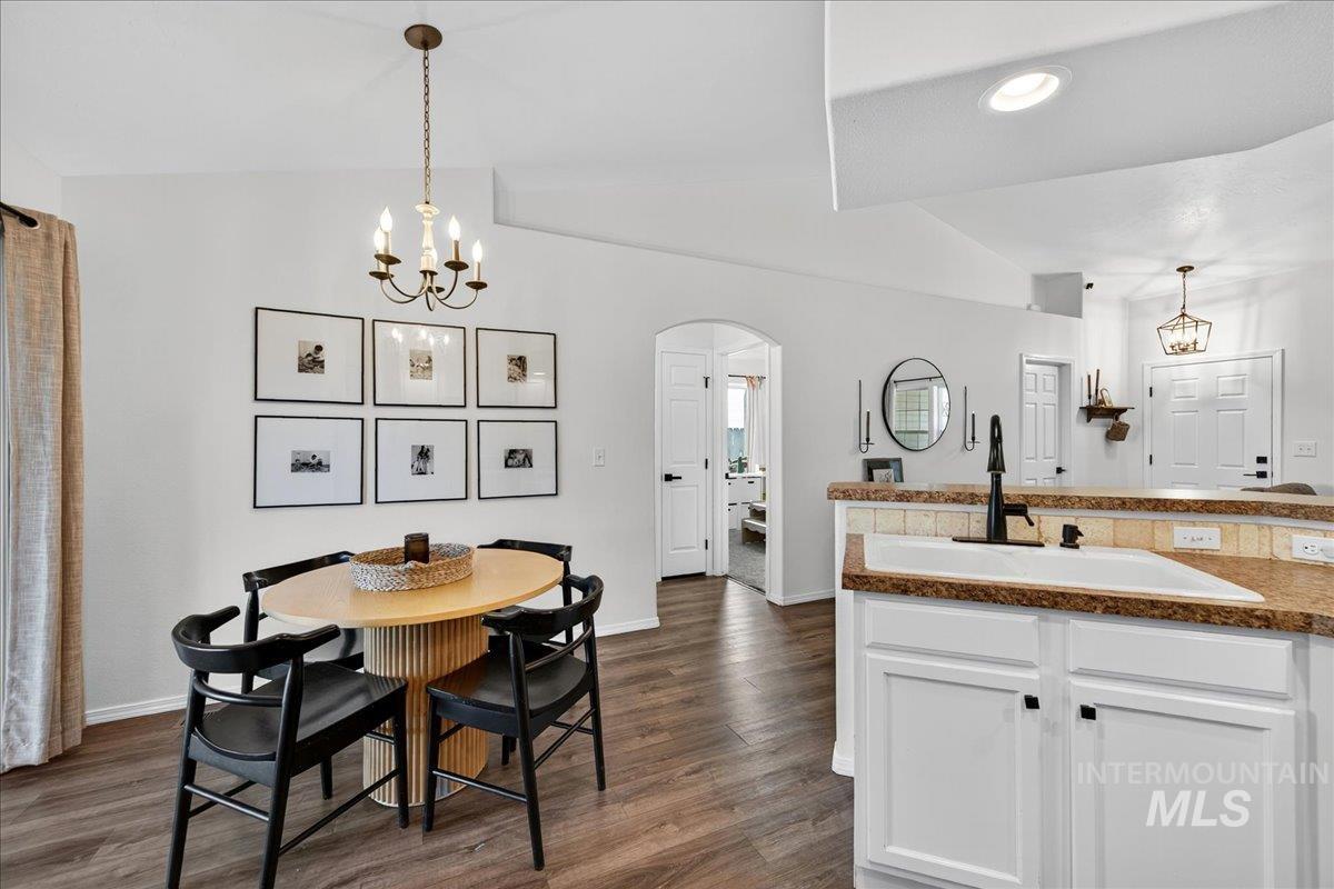 Dining space with a chandelier, arched walkways, vaulted ceiling, dark wood-style floors, and recessed lighting