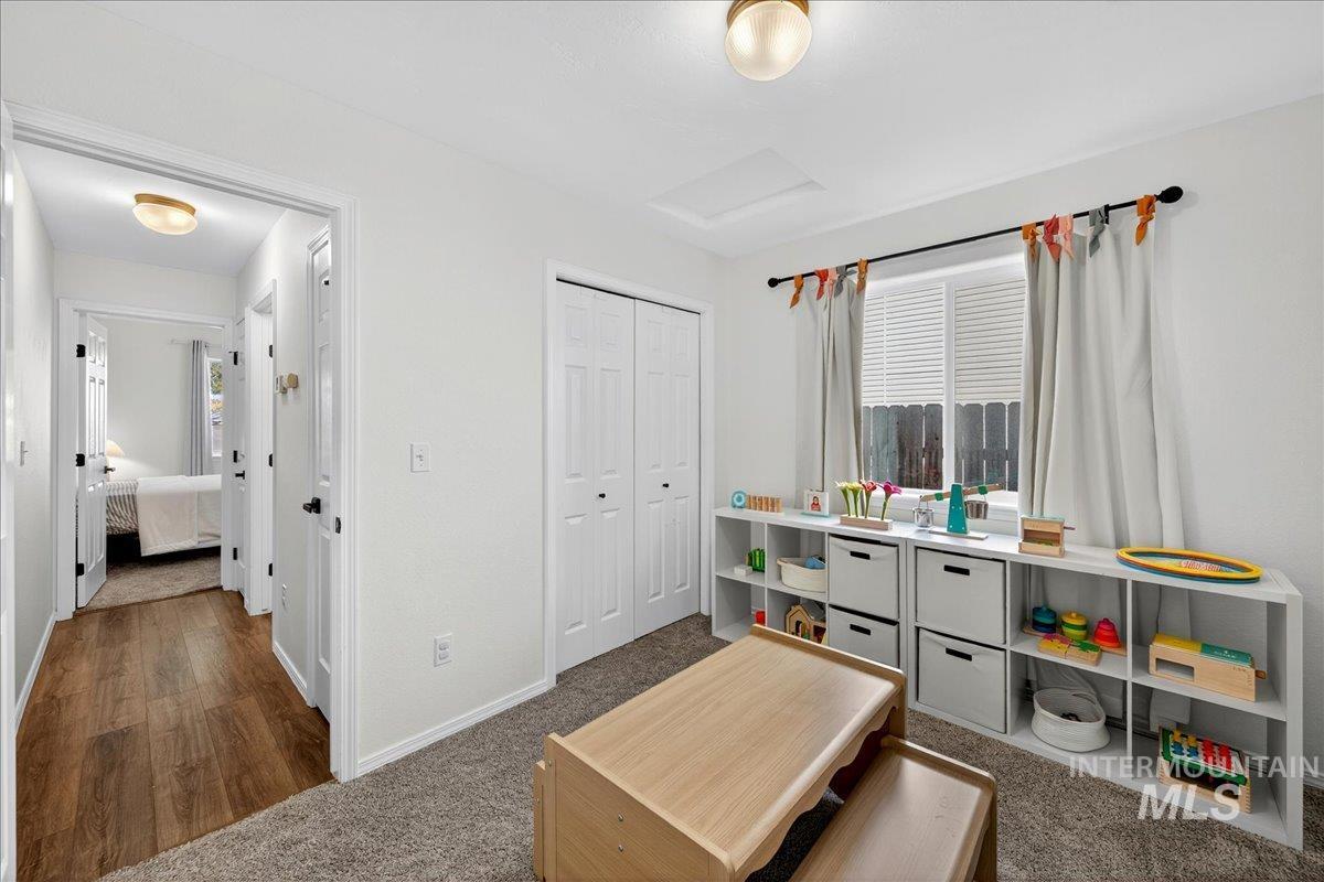 Playroom with dark carpet, attic access, and dark wood finished floors