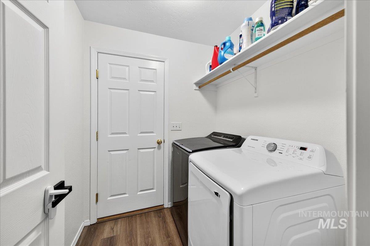 Washroom with dark wood-style floors and washer and clothes dryer