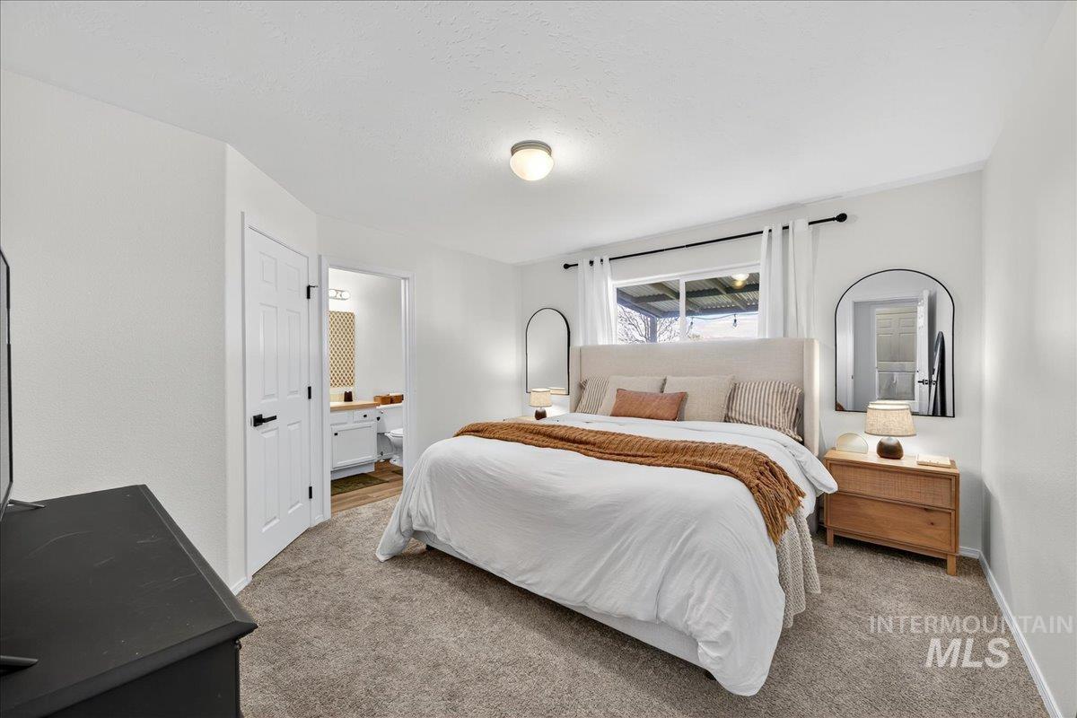 Carpeted bedroom with ensuite bathroom and baseboards