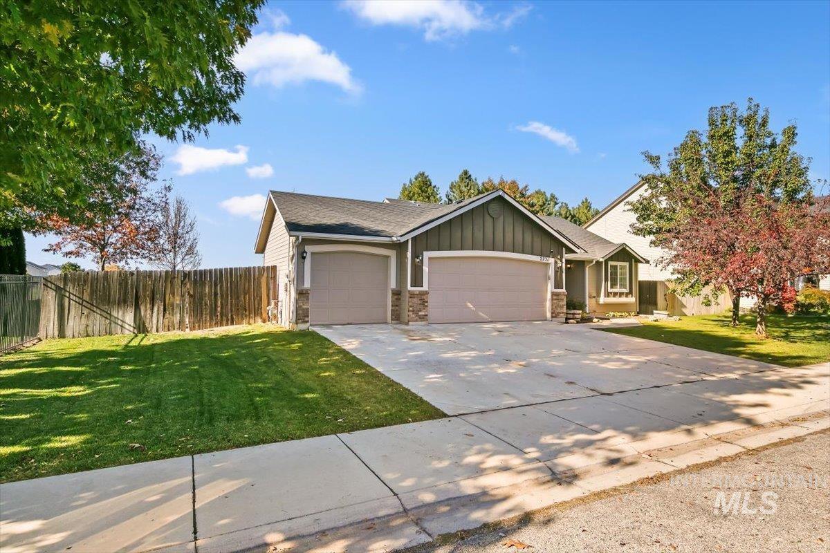 View of front of house featuring an attached garage, concrete driveway, board and batten siding, stone siding, and roof with shingles