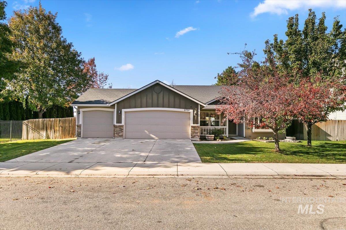 View of front facade with a garage, board and batten siding, concrete driveway, and stone siding
