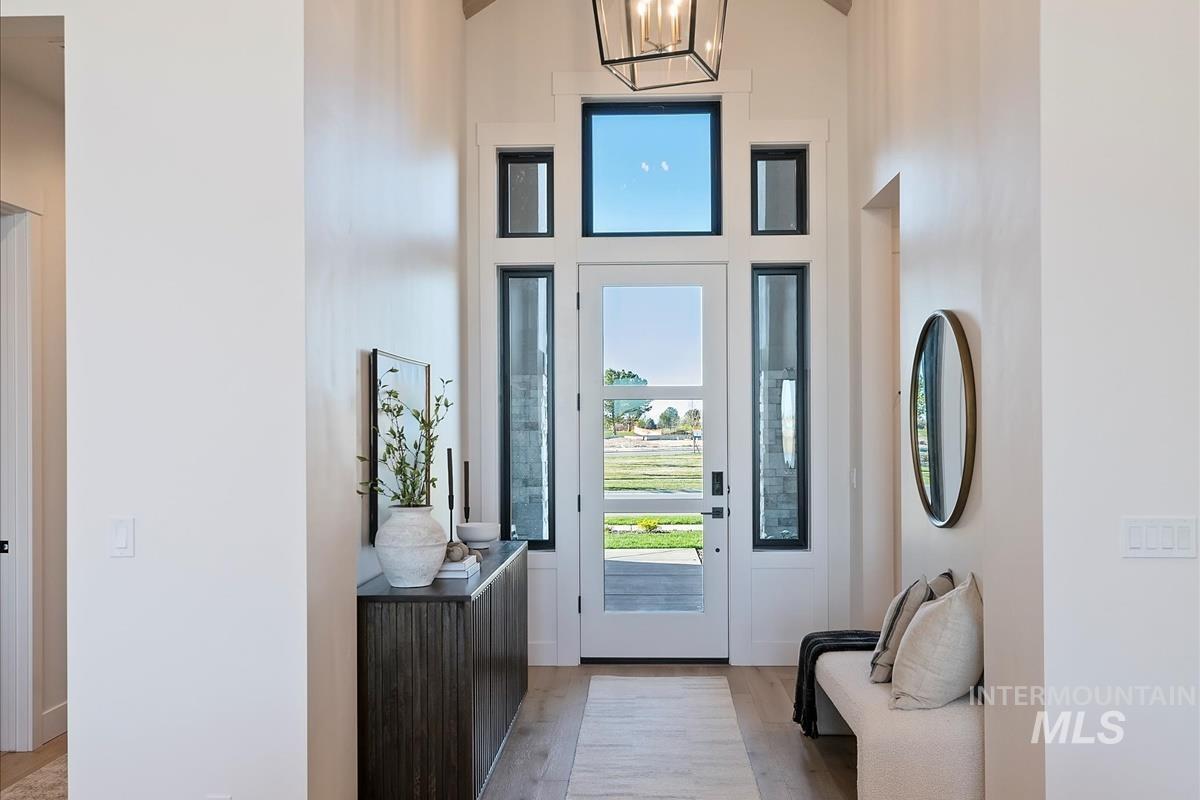 Entrance foyer featuring light wood finished floors, a chandelier, and lofted ceiling