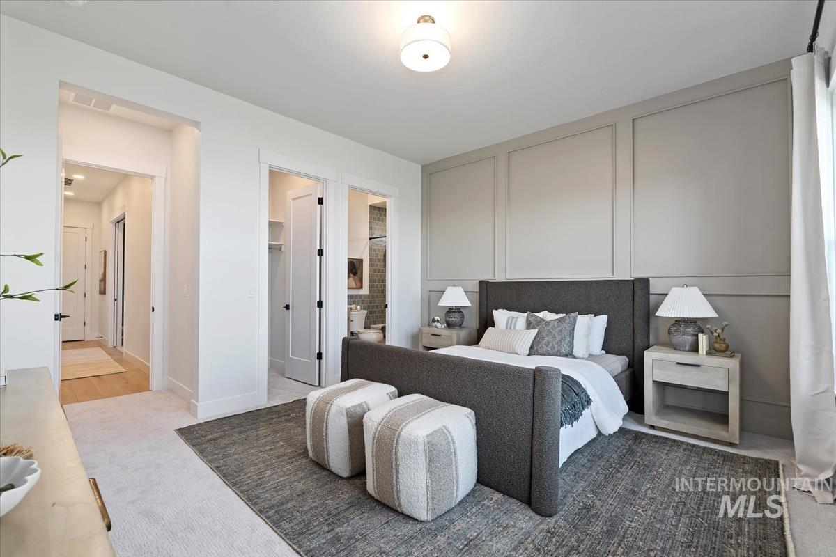 Carpeted bedroom featuring a walk in closet, a decorative wall, and connected bathroom