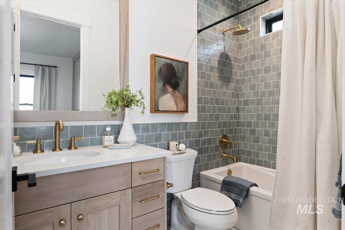 Bathroom with shower / bath combo, tile walls, and vanity