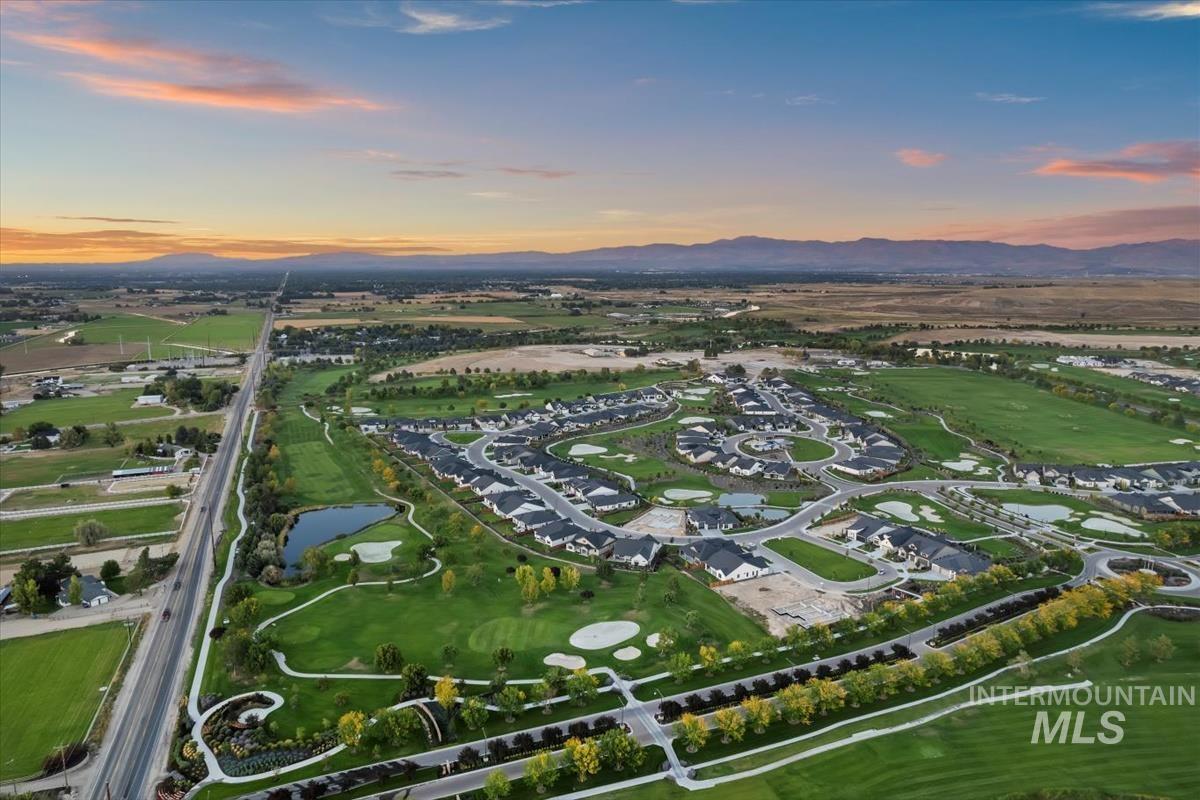 Aerial view of property and surrounding area with a water and mountain view, nearby suburban area, and a local golf course