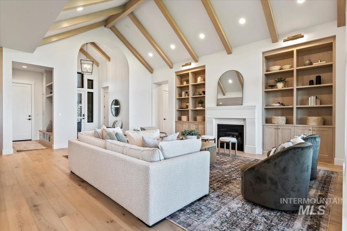 Living area featuring beamed ceiling, high vaulted ceiling, light wood-type flooring, built in shelves, and recessed lighting