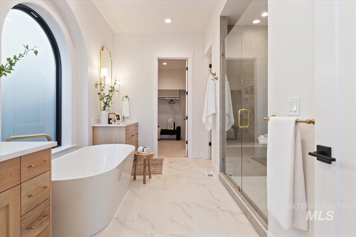 Bathroom featuring vanity, a spacious closet, a freestanding bath, recessed lighting, and a shower stall