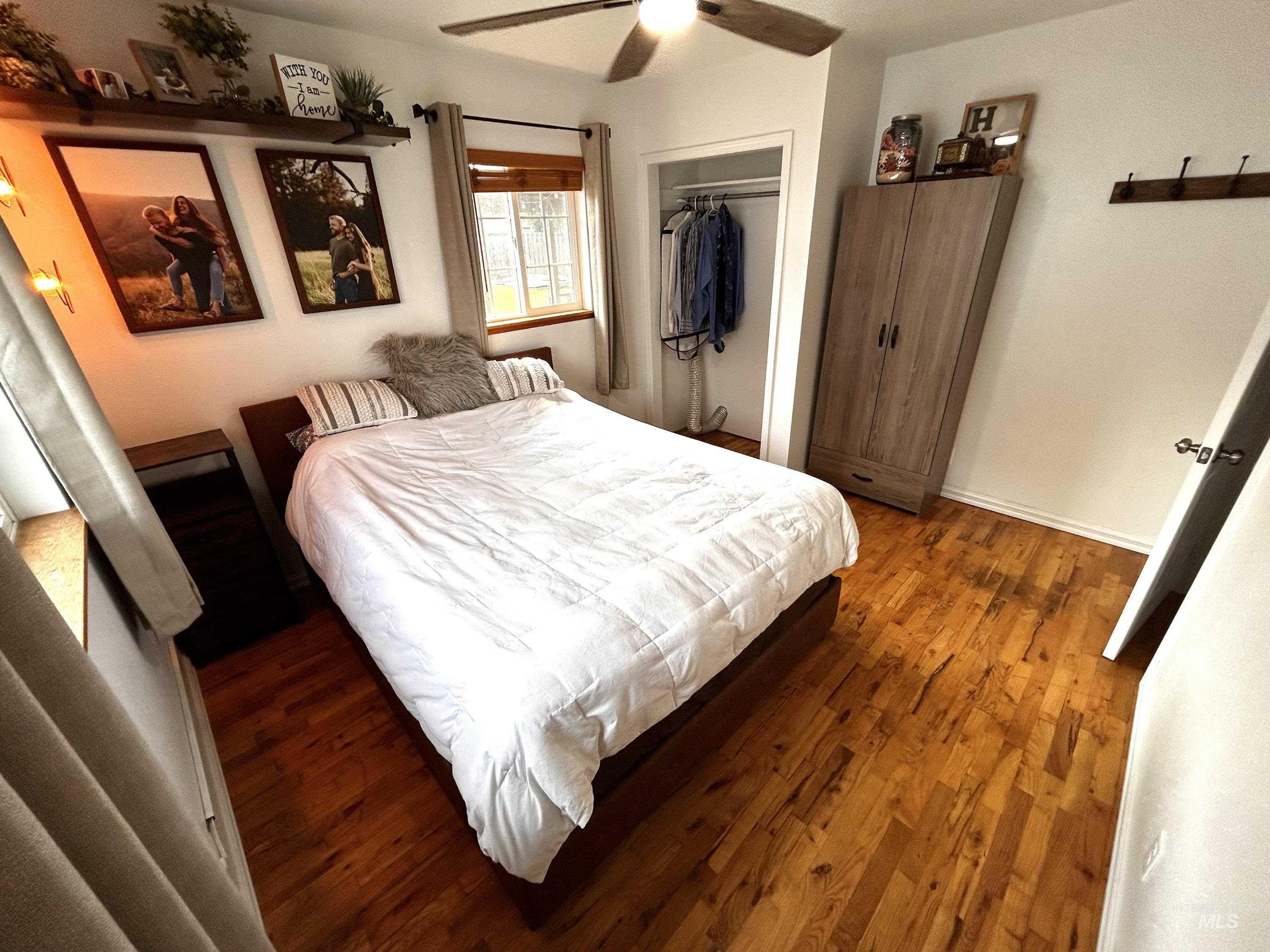 Bedroom with dark wood-type flooring, a closet, and a ceiling fan