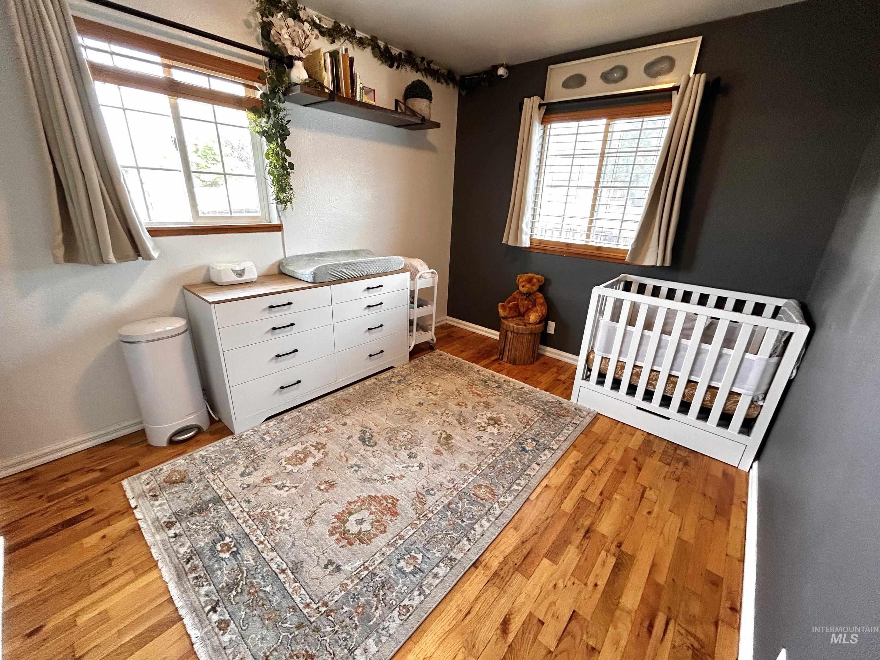 Bedroom featuring light wood-style floors and a crib