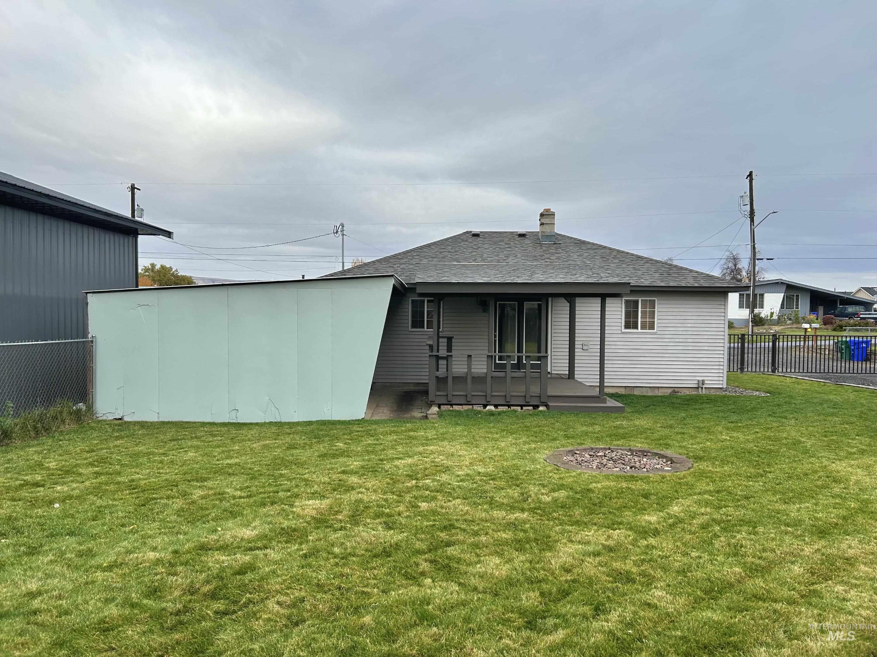 Back of property with a wooden deck, roof with shingles, and a chimney