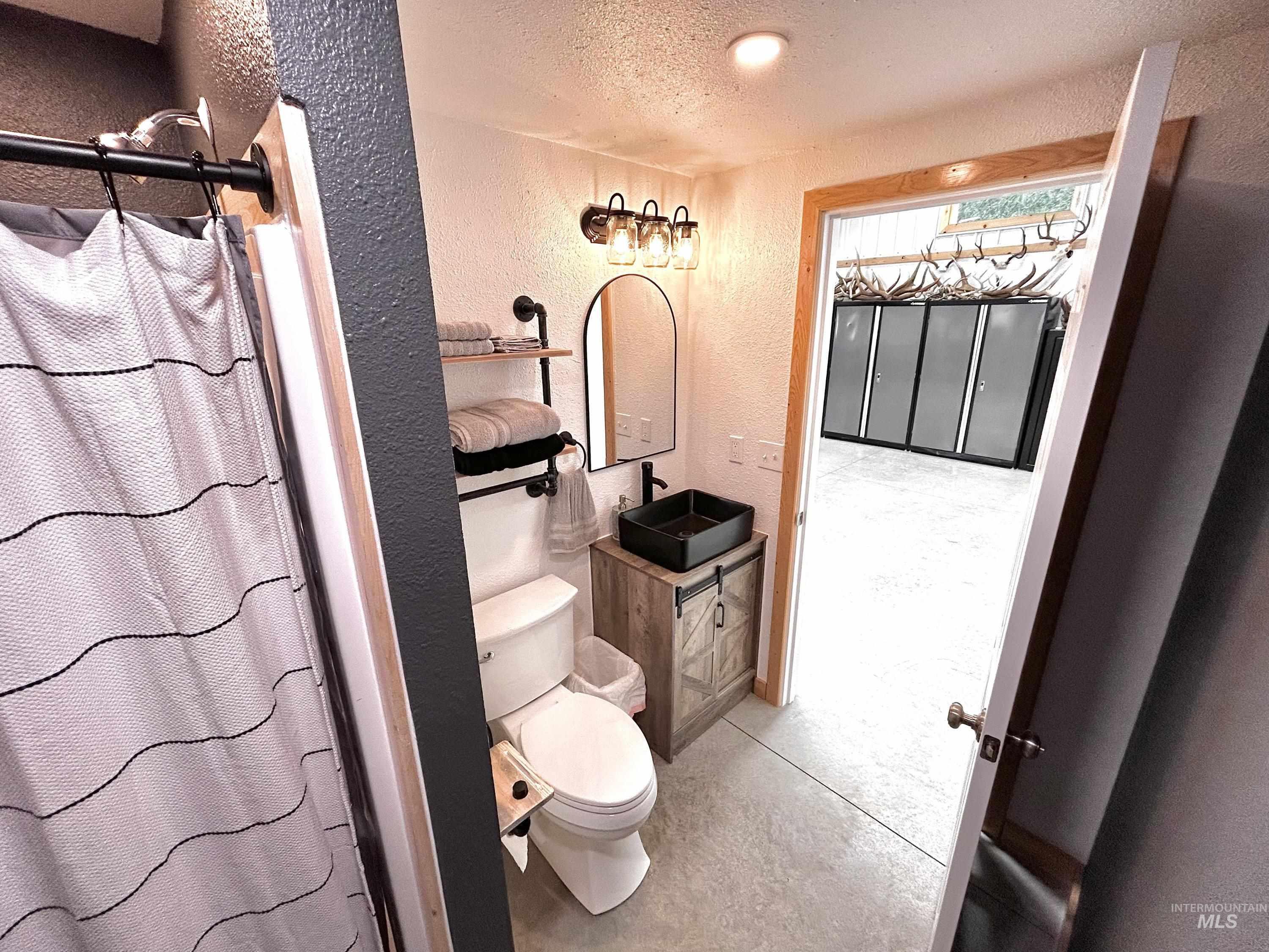 Bathroom featuring a textured wall, a textured ceiling, a stall shower, and vanity