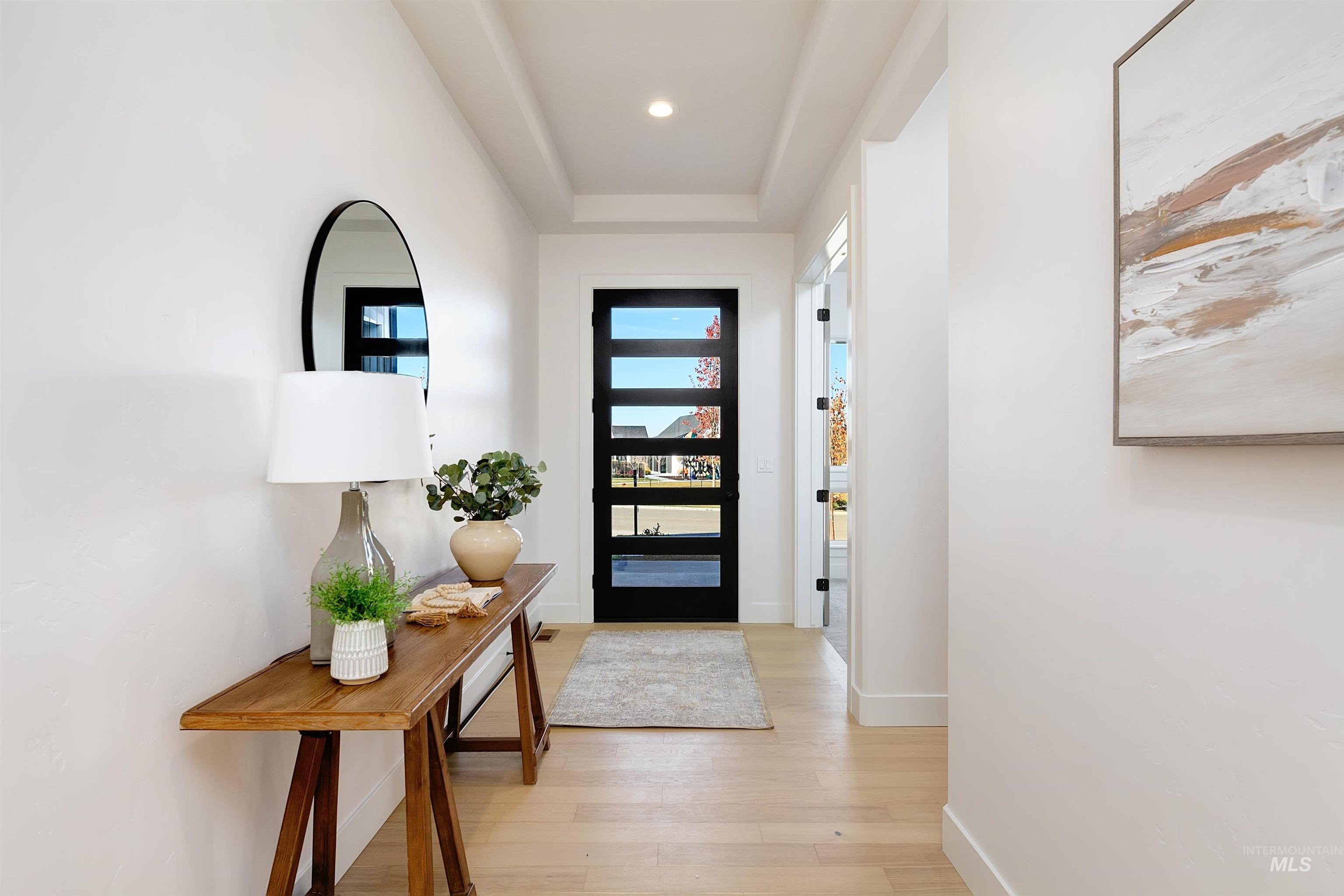 Doorway to outside with wood finished floors, recessed lighting, and a raised ceiling