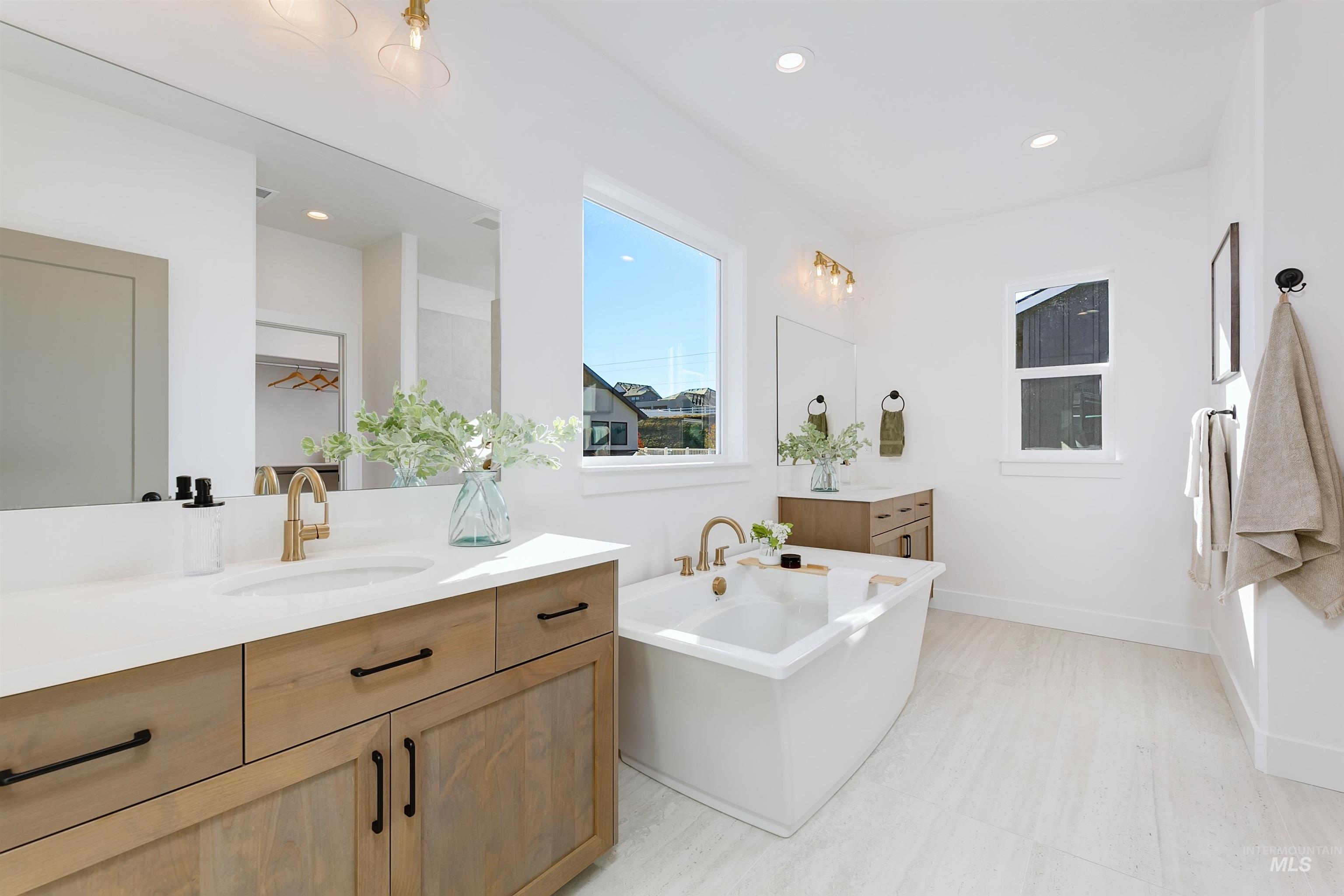 Full bathroom featuring a freestanding bath, two vanities, and recessed lighting