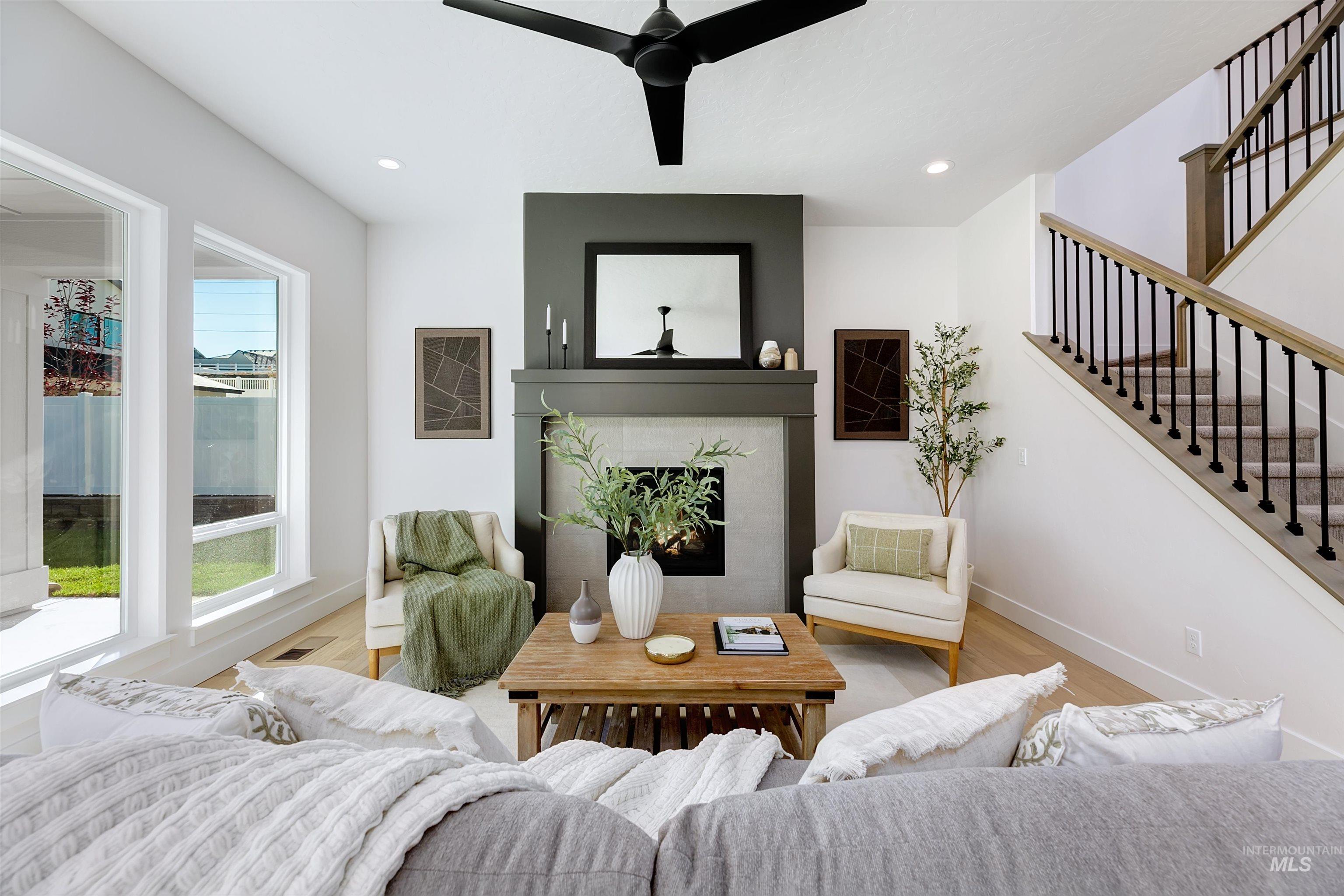 Living area with a fireplace, wood finished floors, recessed lighting, ceiling fan, and stairway