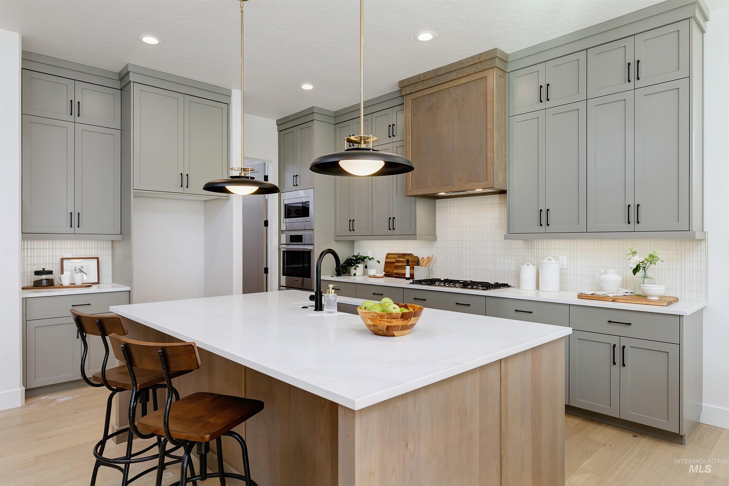 Kitchen featuring gray cabinets, decorative backsplash, pendant lighting, a kitchen island with sink, and recessed lighting