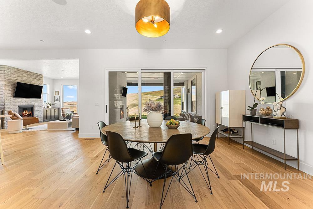 Dining space with light wood-type flooring, healthy amount of natural light, a fireplace, and recessed lighting