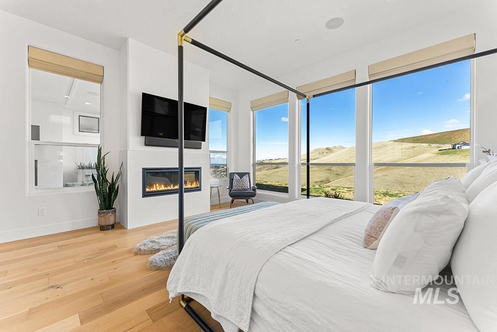 Bedroom with light wood-style floors and a glass covered fireplace