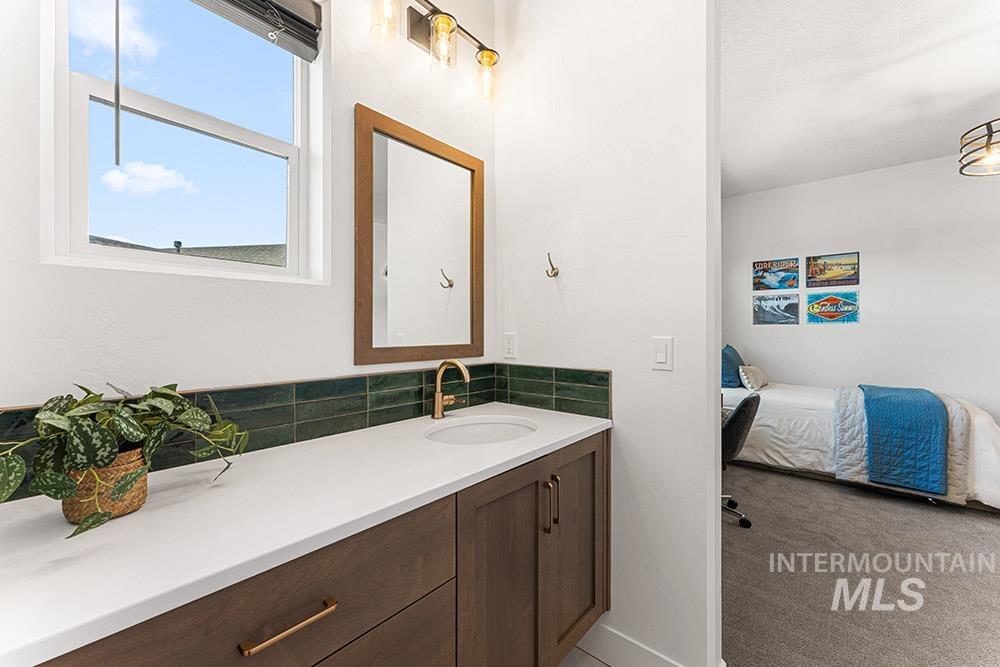 Bathroom with vanity, connected bathroom, and tasteful backsplash