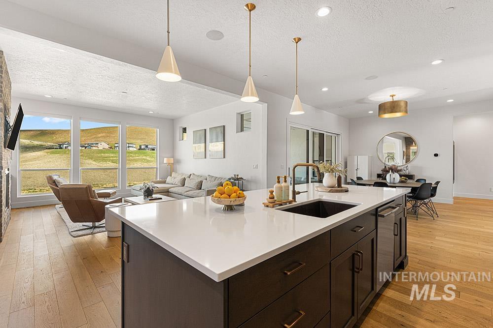 Kitchen featuring open floor plan, a textured ceiling, light countertops, light wood finished floors, and stainless steel dishwasher