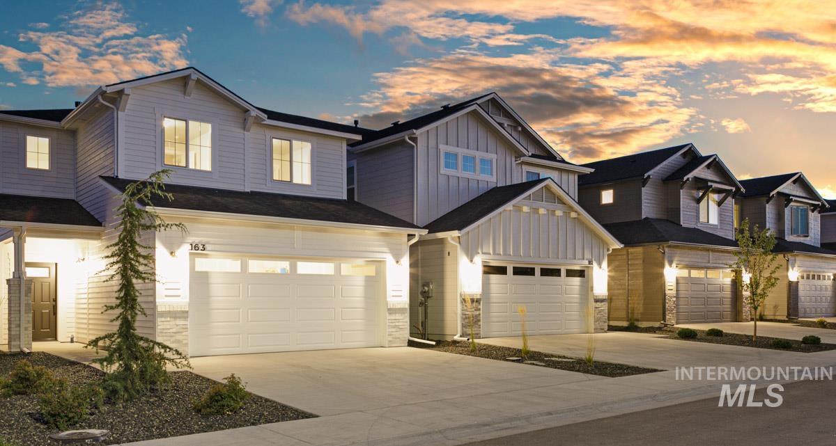 View of front of house with board and batten siding, driveway, an attached garage, and stone siding