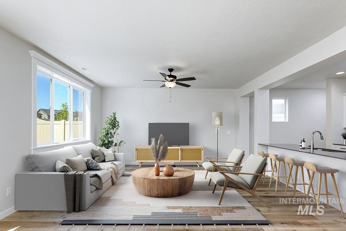 Living room with plenty of natural light, light wood-type flooring, and a ceiling fan