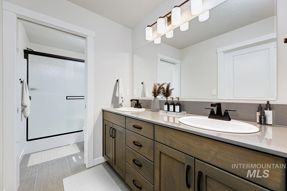 Bathroom with a stall shower, double vanity, and light tile patterned floors