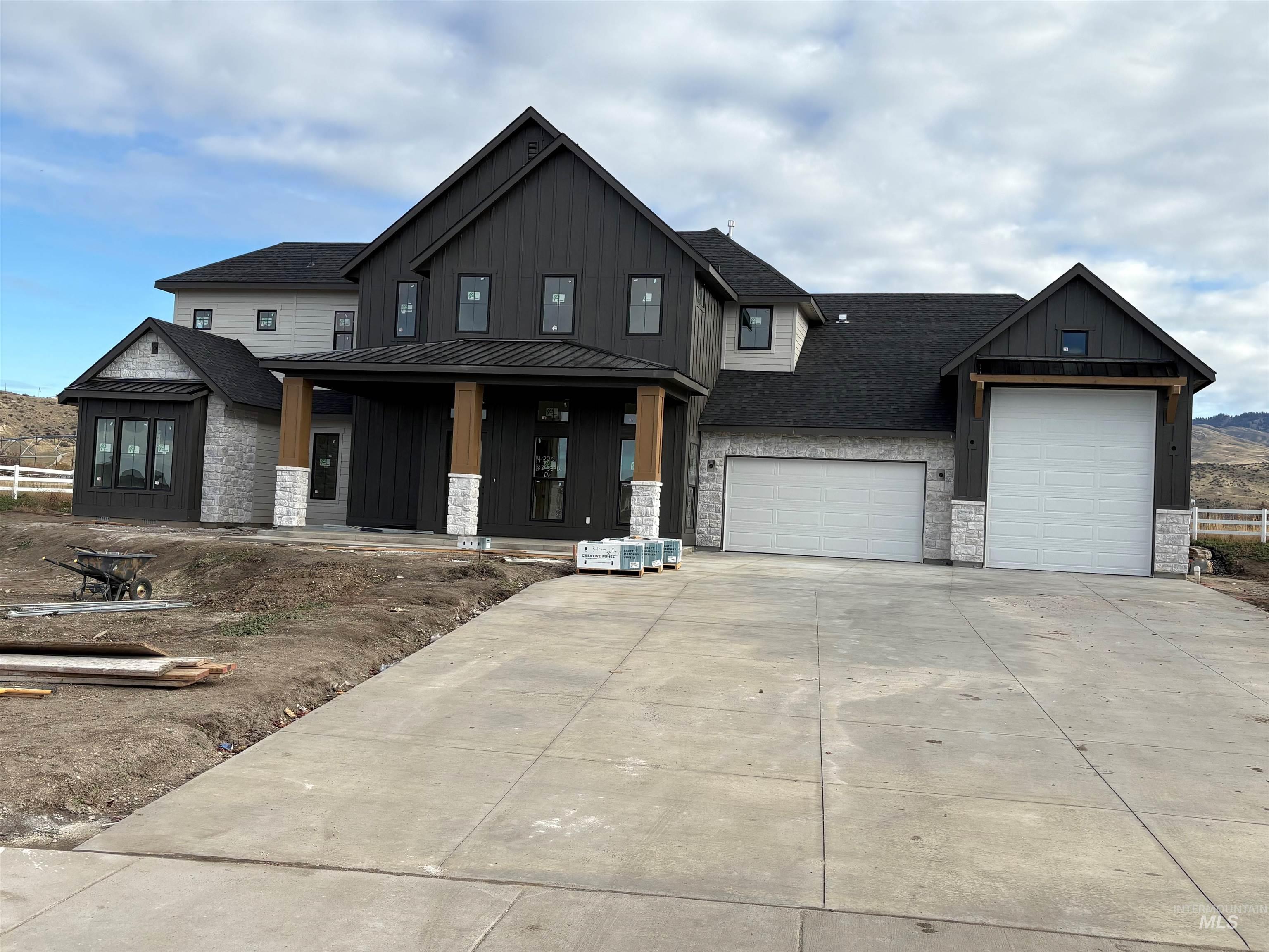 View of front of house with stone siding, a porch, driveway, board and batten siding, and an attached garage