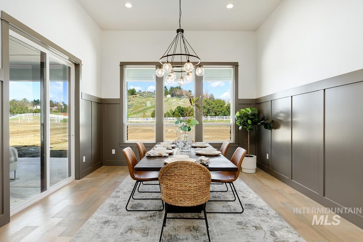 Dining space with a decorative wall, light wood-style floors, a wainscoted wall, a chandelier, and recessed lighting