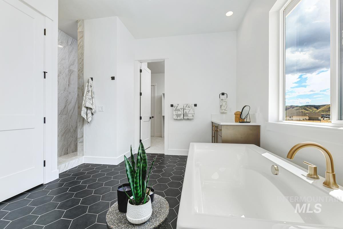 Full bath with a soaking tub, a marble finish shower, recessed lighting, dark tile patterned floors, and vanity