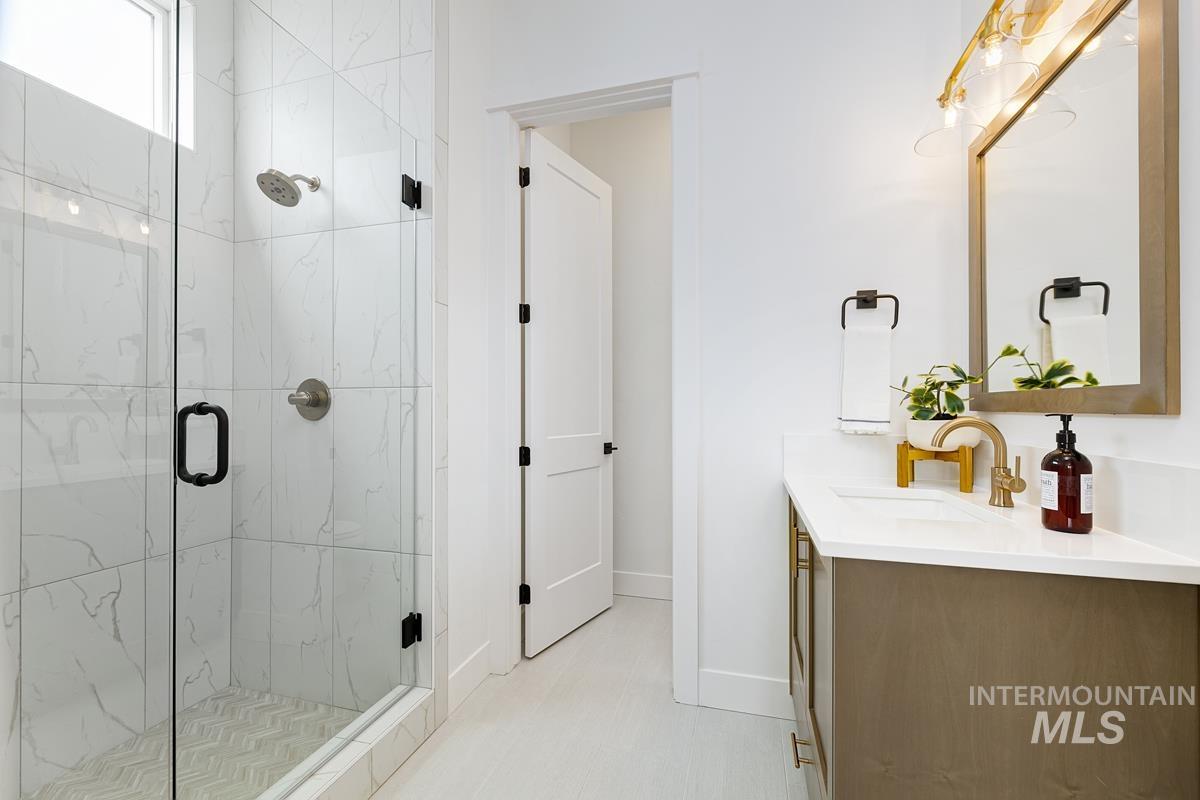 Bathroom featuring vanity and a marble finish shower