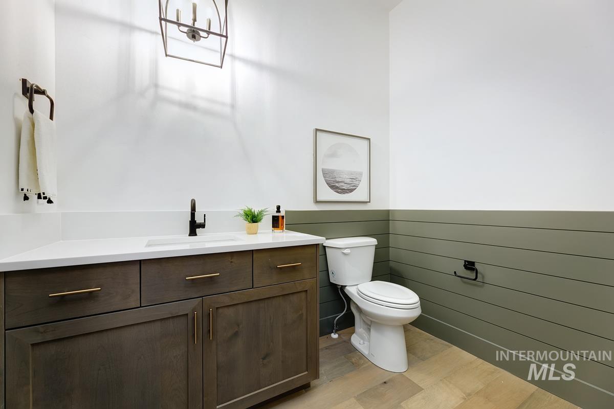 Half bathroom featuring vanity, light wood-style flooring, and wainscoting