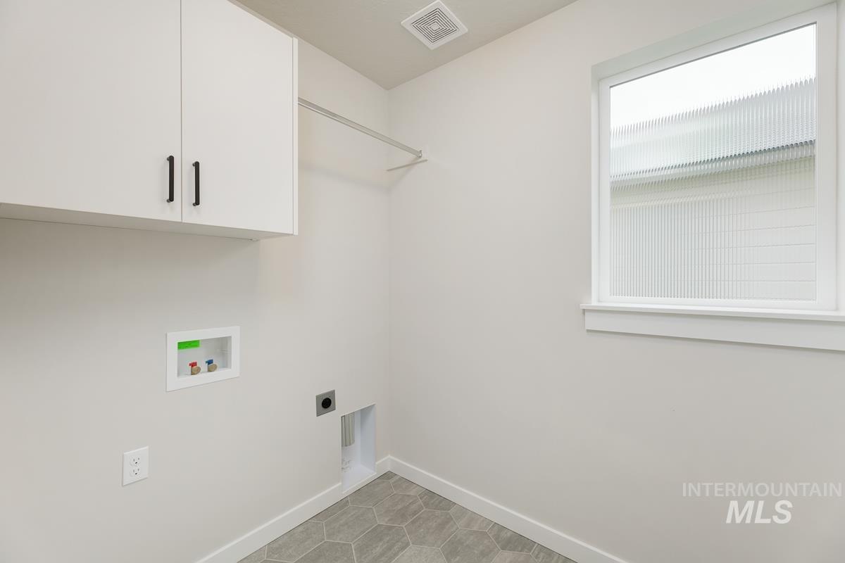 Laundry area featuring cabinet space, hookup for an electric dryer, light tile patterned floors, and hookup for a washing machine