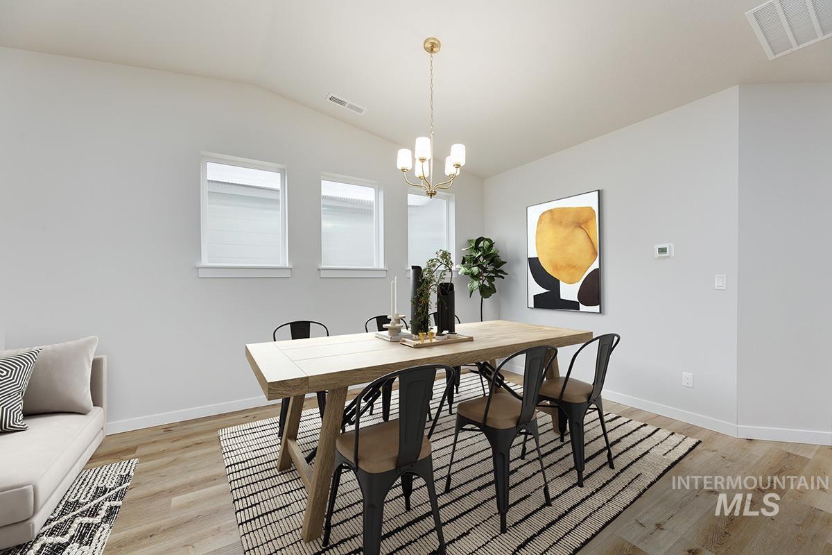 Dining room featuring light wood-style flooring, lofted ceiling, and a chandelier