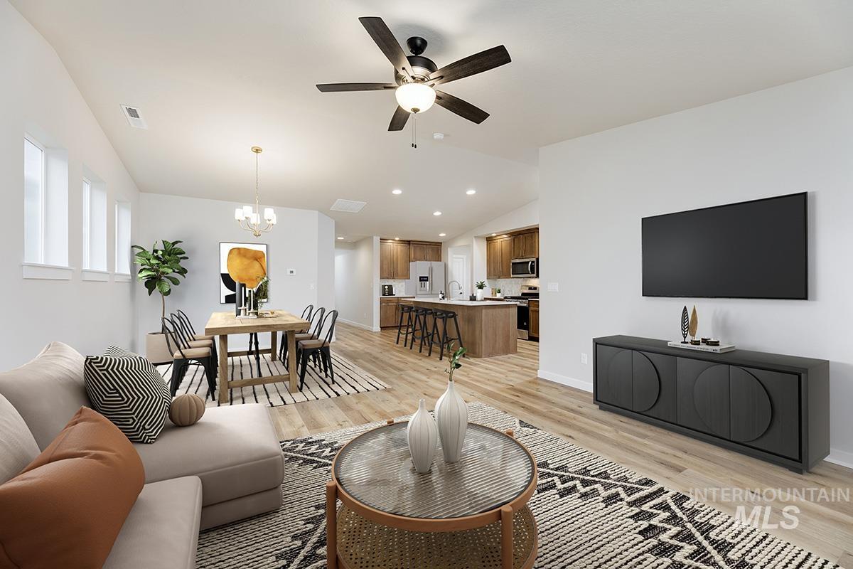Living room with lofted ceiling, a chandelier, light wood-style floors, a ceiling fan, and recessed lighting