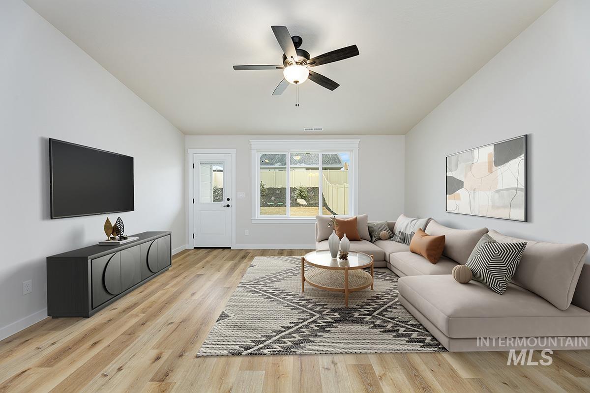 Living area with light wood-style flooring, a ceiling fan, and lofted ceiling