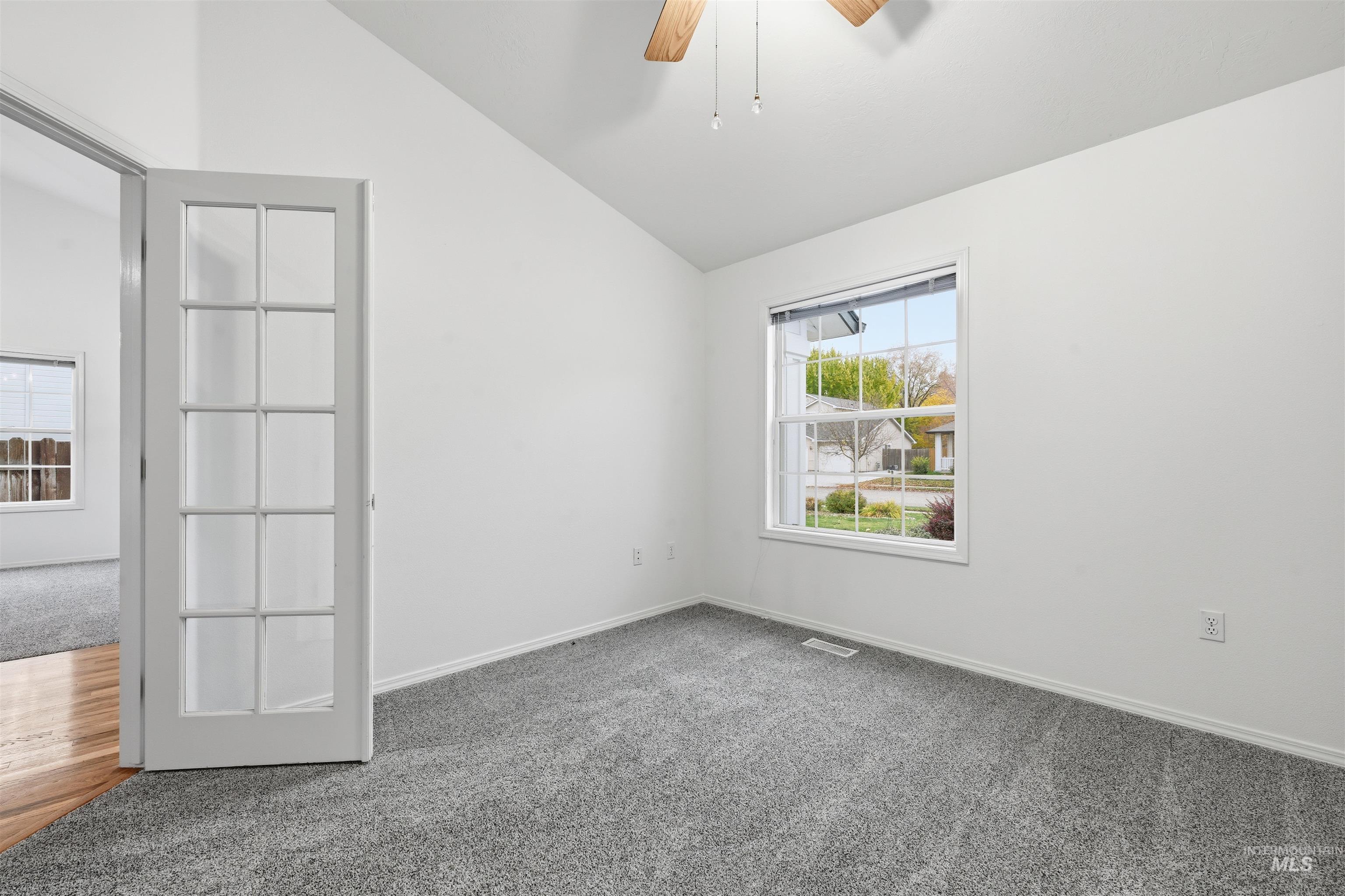 Carpeted spare room with vaulted ceiling and ceiling fan