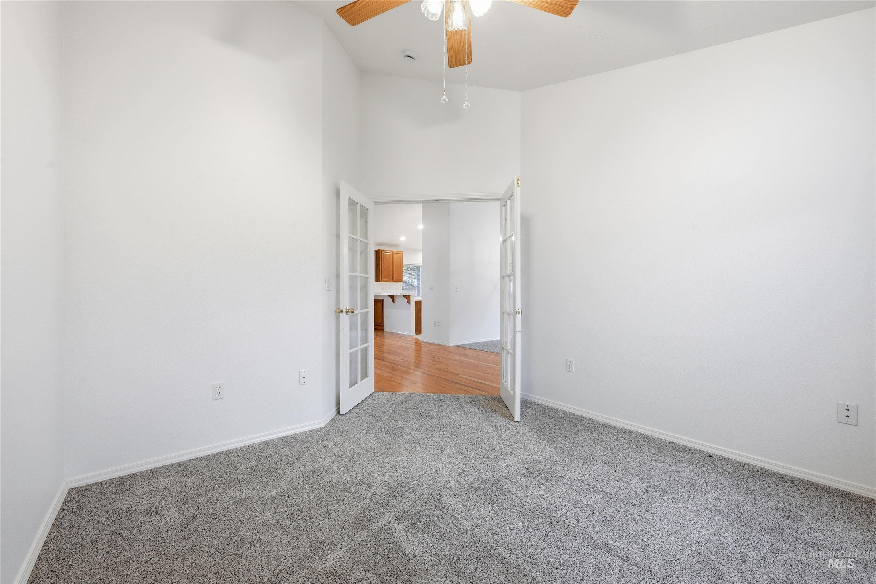 Unfurnished bedroom with carpet floors, a towering ceiling, a ceiling fan, and french doors
