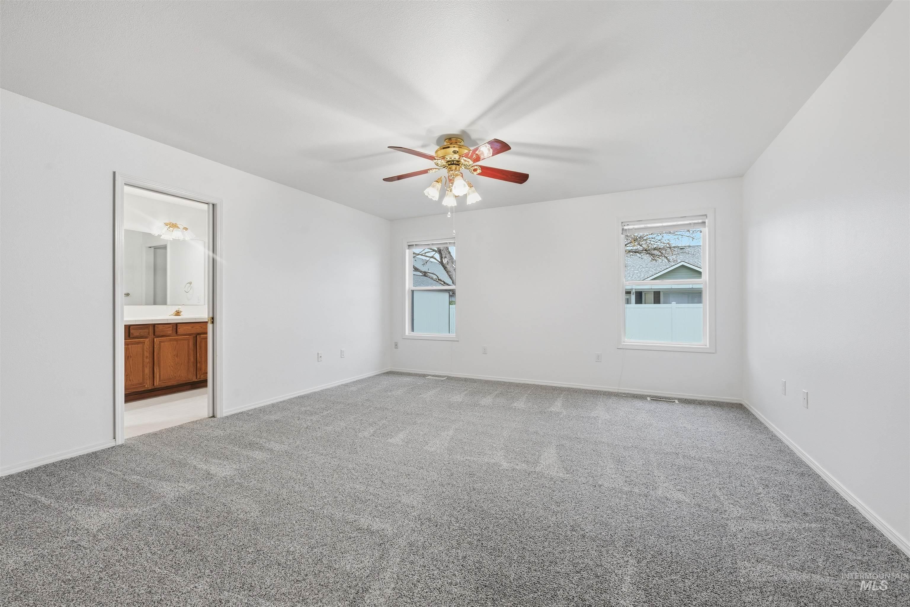 Unfurnished bedroom with light carpet, ceiling fan, and ensuite bath