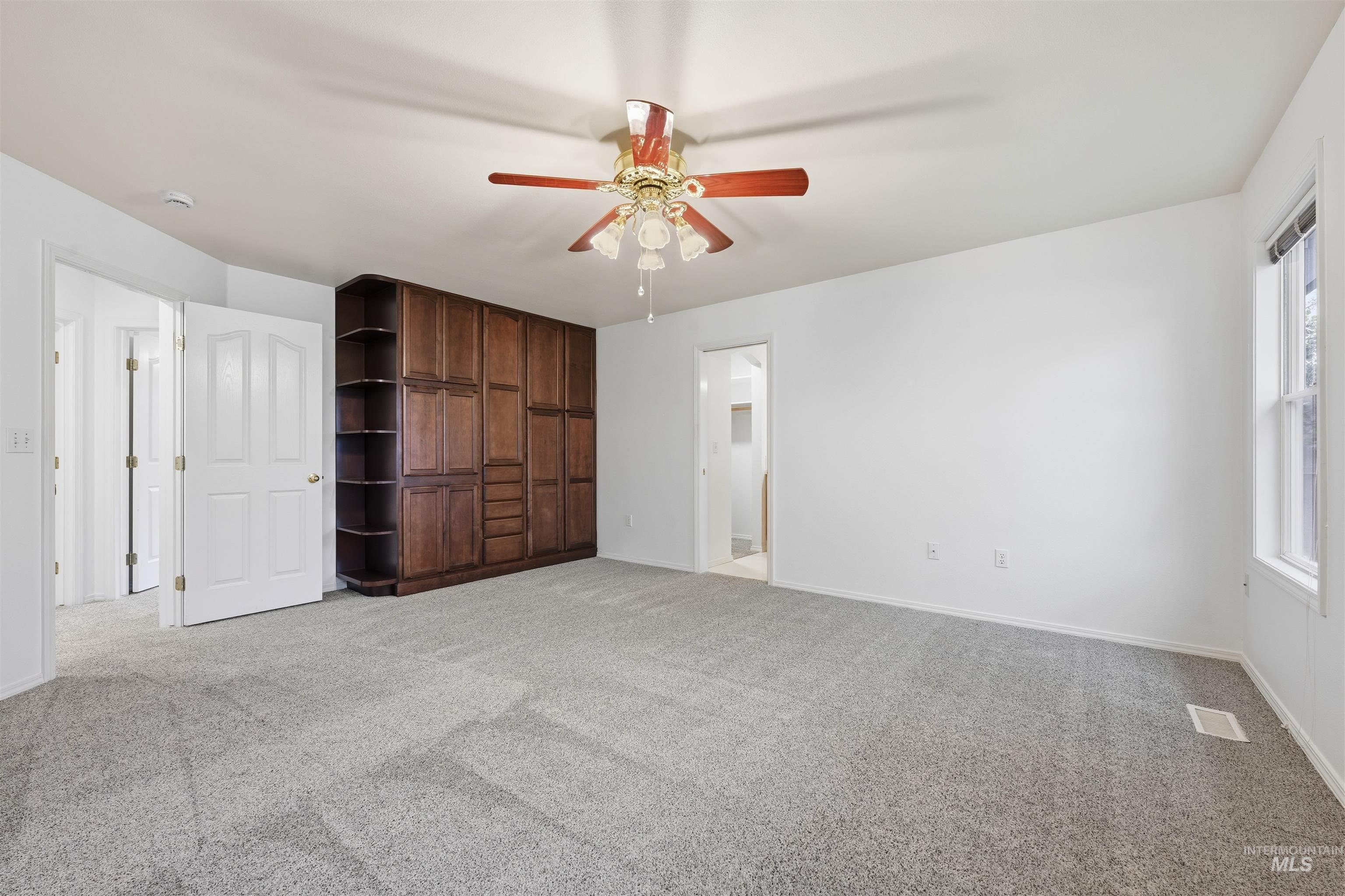 Unfurnished bedroom featuring light colored carpet, a ceiling fan, and ensuite bathroom