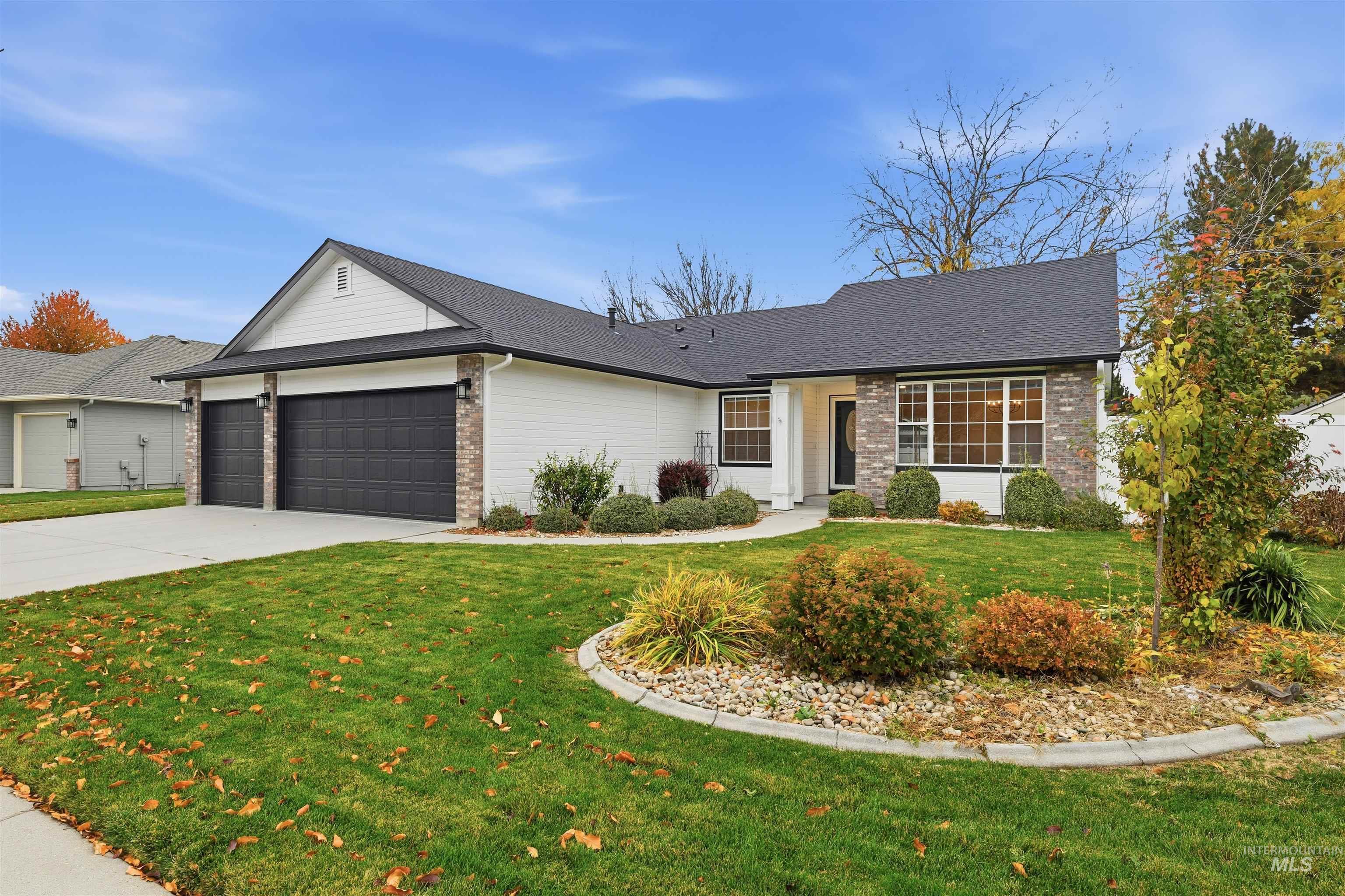 Ranch-style house with a front lawn, an attached garage, concrete driveway, roof with shingles, and brick siding