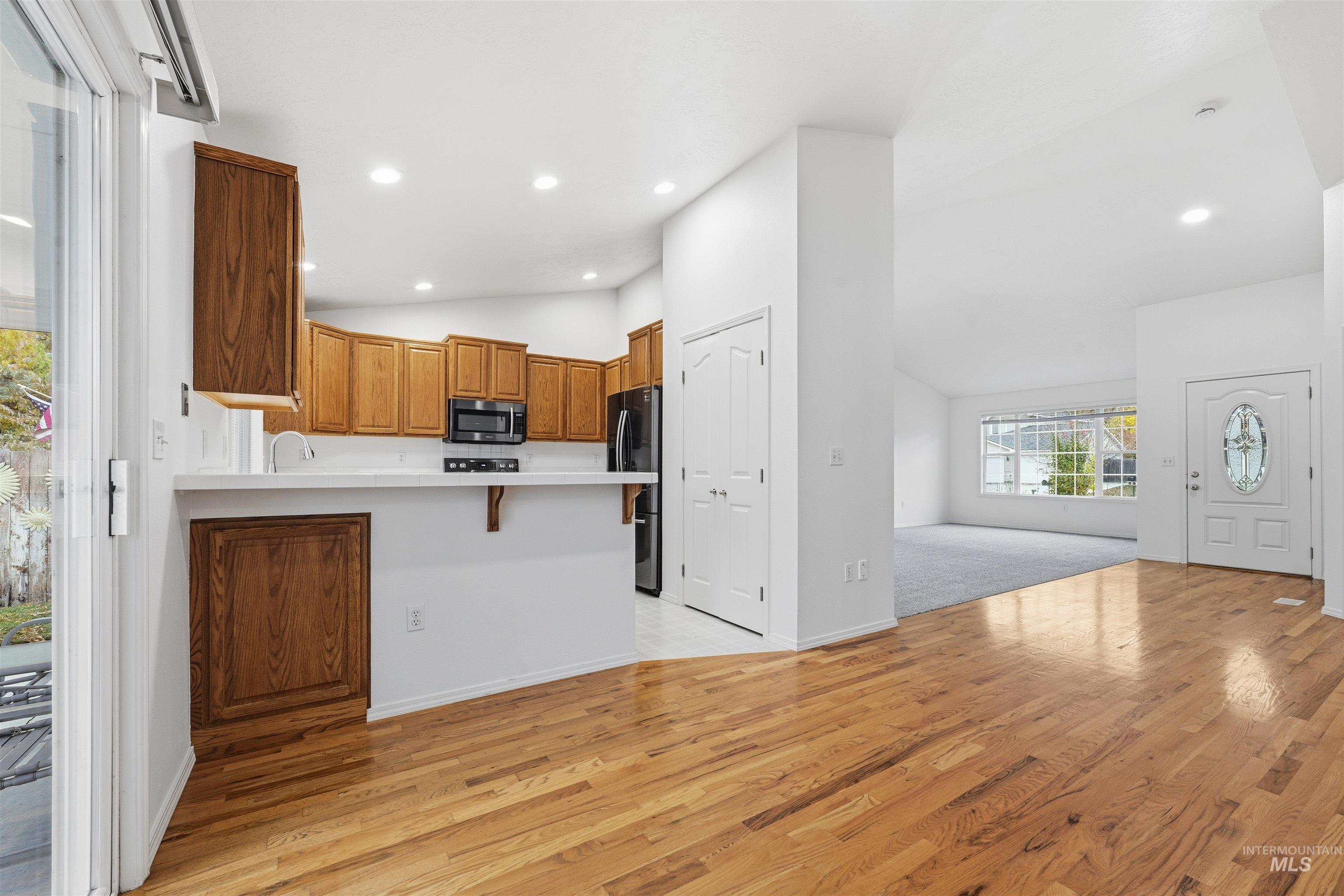 Kitchen with a breakfast bar area, a peninsula, light wood-type flooring, light countertops, and open floor plan