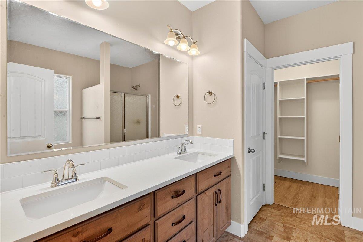 Full bathroom featuring a shower stall, a spacious closet, and double vanity