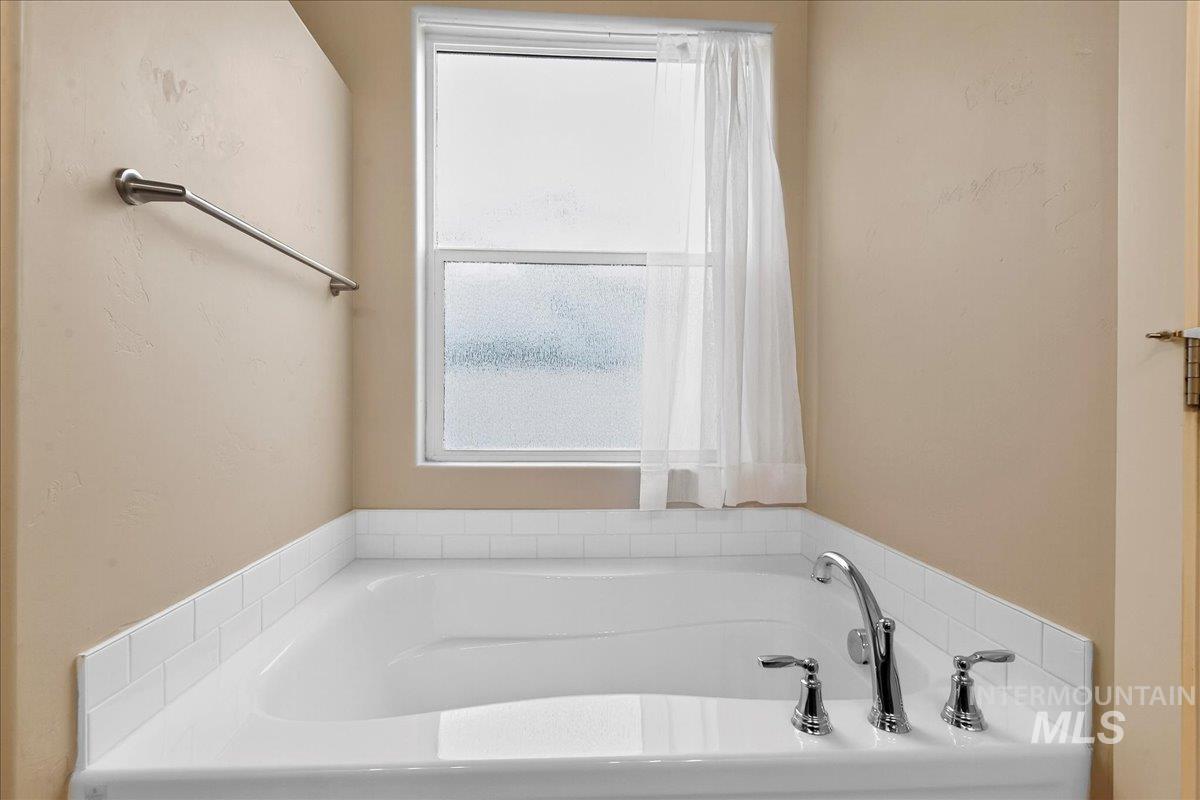 Full bathroom with healthy amount of natural light and a bath