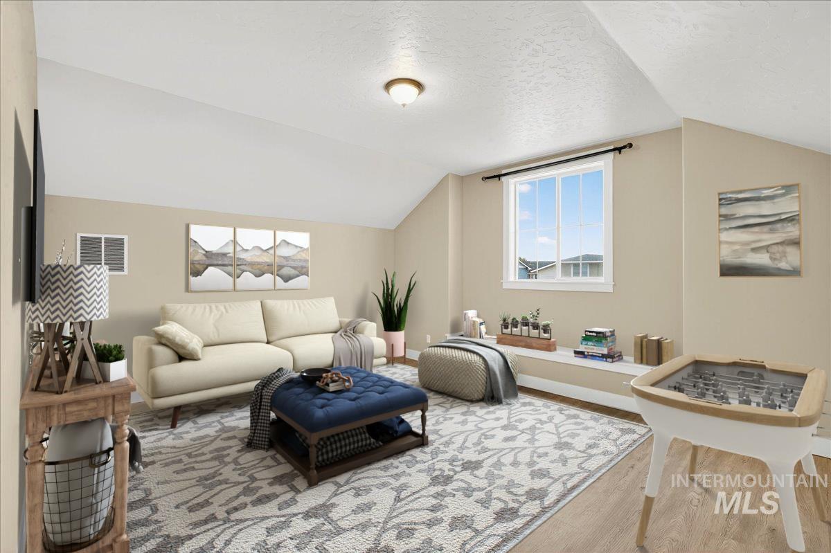 Living area featuring wood finished floors, a textured ceiling, and vaulted ceiling