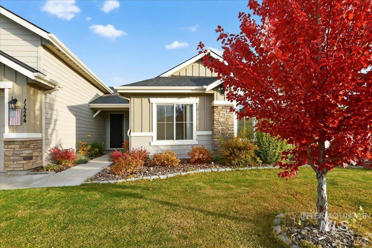View of side of home with board and batten siding, stone siding, and a yard